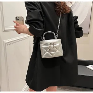 Detail of silver quilted box bag with metal handle and chain strap shown on model