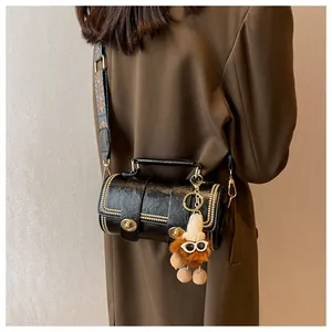 Details der schwarzen Zylinder-Tasche mit Goldnieten und Ethno-Trageriemen