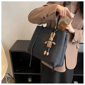 Detail of black minimalist tote bag showing spacious interior with phone and cute rabbit charm