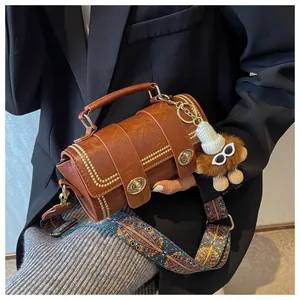 Detail der braunen Zylindertasche mit Goldnieten und ethnischem breitem Tragegurt