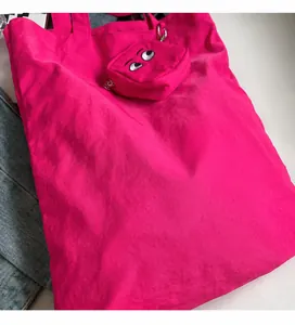 Gros plan du sac cabas rose fuchsia avec broderie œil de monstre sur la pochette latérale