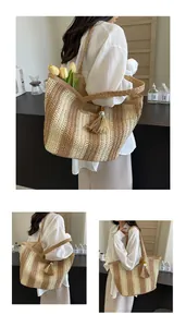 Dettaglio di una borsa tote in paglia a righe con manici intrecciati e nappa decorativa