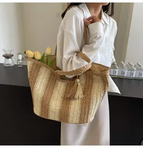Borsa tote in paglia a righe verticali indossata da una modella in una caffetteria