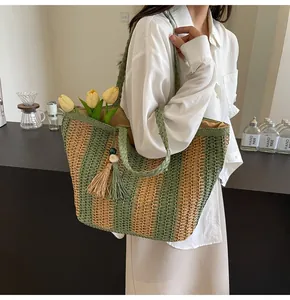 Dettaglio di una borsa tote in paglia a righe verdi con un elegante pendente a nappa