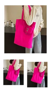 Detalle del bolso tote de lona rosa con bordado de monstruo y monedero pequeño a juego