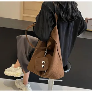 Detalle de un bolso Hobo marrón plegable con bordado de ojos de pequeño monstruo