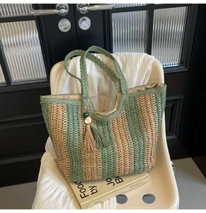Dettaglio borsa di paglia a righe verticali colorate con manici tondi e nappina