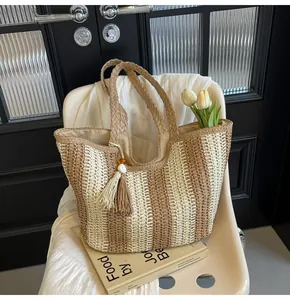 Dettaglio della borsa tote in paglia a righe con nappe decorative in seta bicolore