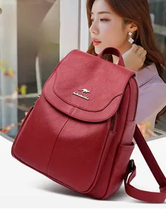 Detail of red lychee textured leather backpack featuring a metal kangaroo logo