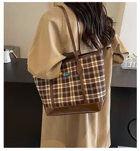 Detail of vintage brown plaid tote bag with embroidery on shoulder of model
