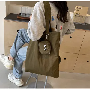 Detalle de bolso tote de nailon verde militar con bordado de ojos de monstruo