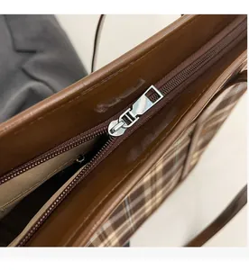 Detailed close-up of the smooth silver metal zipper on the vintage plaid tote bag