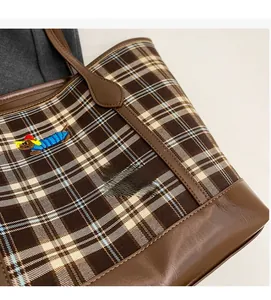 Detail of plaid tote bag featuring dachshund embroidery and premium brown leather straps