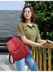 Detail of red faux leather backpack with metallic kangaroo emblem and flap closure