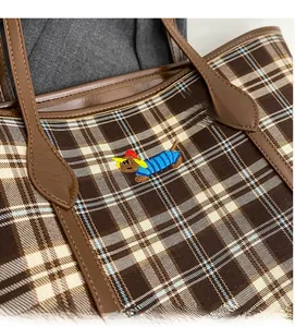 Detail of plaid tote bag featuring a cute dachshund embroidery and brown leather trim