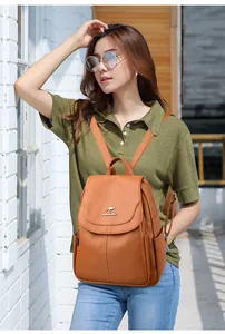Outdoor shot of woman wearing a brown lychee leather backpack with metal kangaroo logo