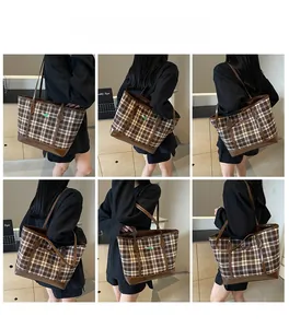 Detail view of large brown plaid tote bag with leather trim on model shoulder