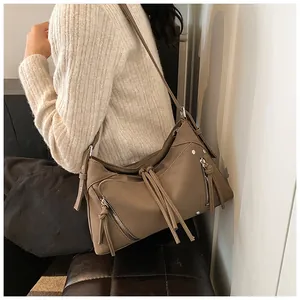 Dettaglio della borsa a tracolla kaki in ecopelle con borchie metalliche e lunghe nappe decorative