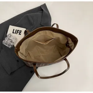 Detailed interior of a brown plaid tote bag featuring a zip pocket and spacious lining