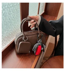 Close-up of a brown leather Boston bag with decorative heart and pool ball charms