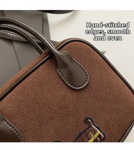 Close-up of brown suede bag showing detailed embroidery and premium stitching craftsmanship