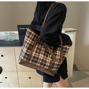 Detail view of brown checkered tote bag with puppy embroidery on female model shoulder
