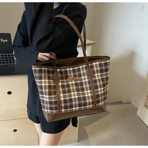 Detail of checkered tote bag with dachshund embroidery and brown leather trim on a model