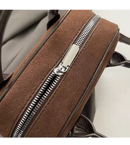 Detailed macro view of smooth metal zipper and suede texture on fashionable brown handbag
