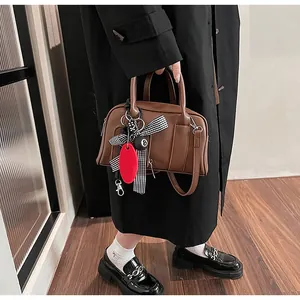 Brown Boston handbag detail with checkered ribbon and ball pendant in a retro look