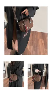 Detail of dark brown leather tote featuring colorful dachshund embroidery and dog charm