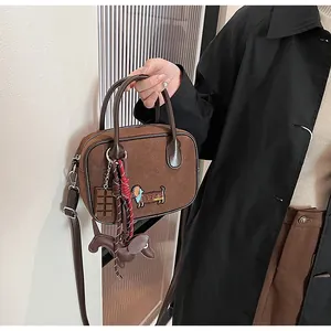 Detail of dark brown suede handbag featuring embroidered dachshund and chocolate charms