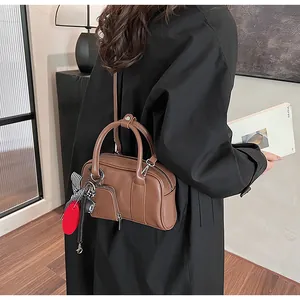 Detail of brown leather crossbody bag with decorative heart charm and silk scarf wrap