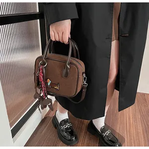 Detail of a brown suede handbag featuring dachshund embroidery and woven dog charm