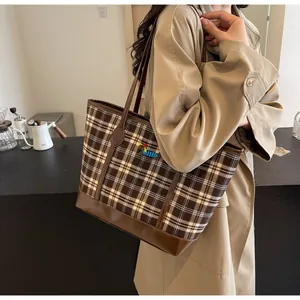Close-up of vintage brown plaid tote bag with embroidery details on a fashion model