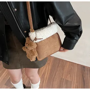 Close-up of brown suede crossbody bag with fuzzy white sherpa trim and bear charm