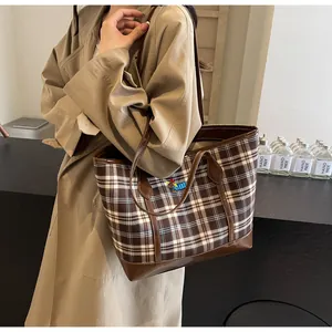 Detail of vintage plaid tote bag with brown leather base and colorful embroidery