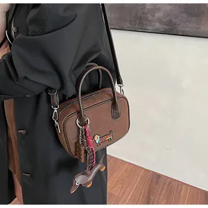 Detail of coffee brown suede handbag with dachshund embroidery and cute bag charms