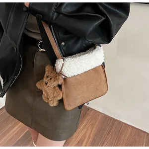 Detail of plush brown suede bag with white faux shearling trim and cute bear charm