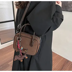 Close-up of dark brown suede handbag featuring dachshund embroidery and matching leather charm