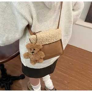 Detail of plush crossbody bag with beige faux shearling flap and brown bear charm