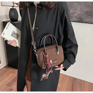 Detail showing brown suede tote with dachshund embroidery and cute chocolate charms