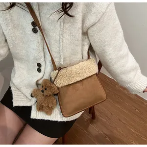 Detail of suede and faux fur crossbody bag with a cute brown bear charm accessory