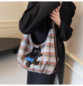 Detail der Retro-Karo-Woll-Tote-Bag mit kreativer Katzenstickerei und braunem Lederriemen