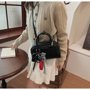 Close-up of black crossbody bag featuring a checkered bow and billiard ball charm detail