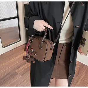Detail of dark brown suede handbag with dachshund embroidery and cute dog bag charm