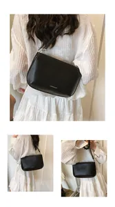 Détail d'un sac à bandoulière en cuir noir mat avec logo Lukadi blanc et bandoulière