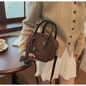 Detail of dark brown suede handbag featuring dachshund embroidery and chocolate charms
