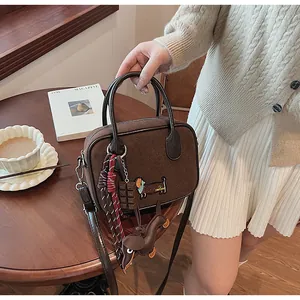 Brown suede bag detail with dachshund embroidery and chocolate block charm accessory