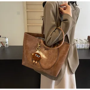 Sac cabas marron vintage avec pendentif en peluche porté par un mannequin en style urbain