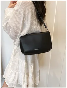 Détail du sac bandoulière noir en cuir mat souple avec logo blanc sur le devant